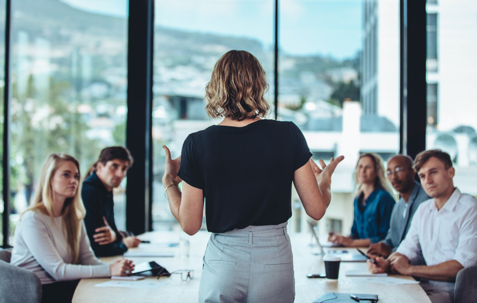 A businesswoman explaining new strategies to coworkers during conference meeting in office.