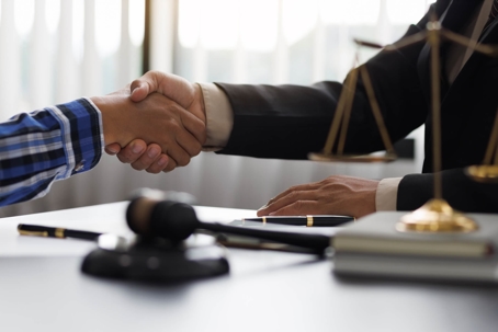 Two men shaking hands with gavel on table